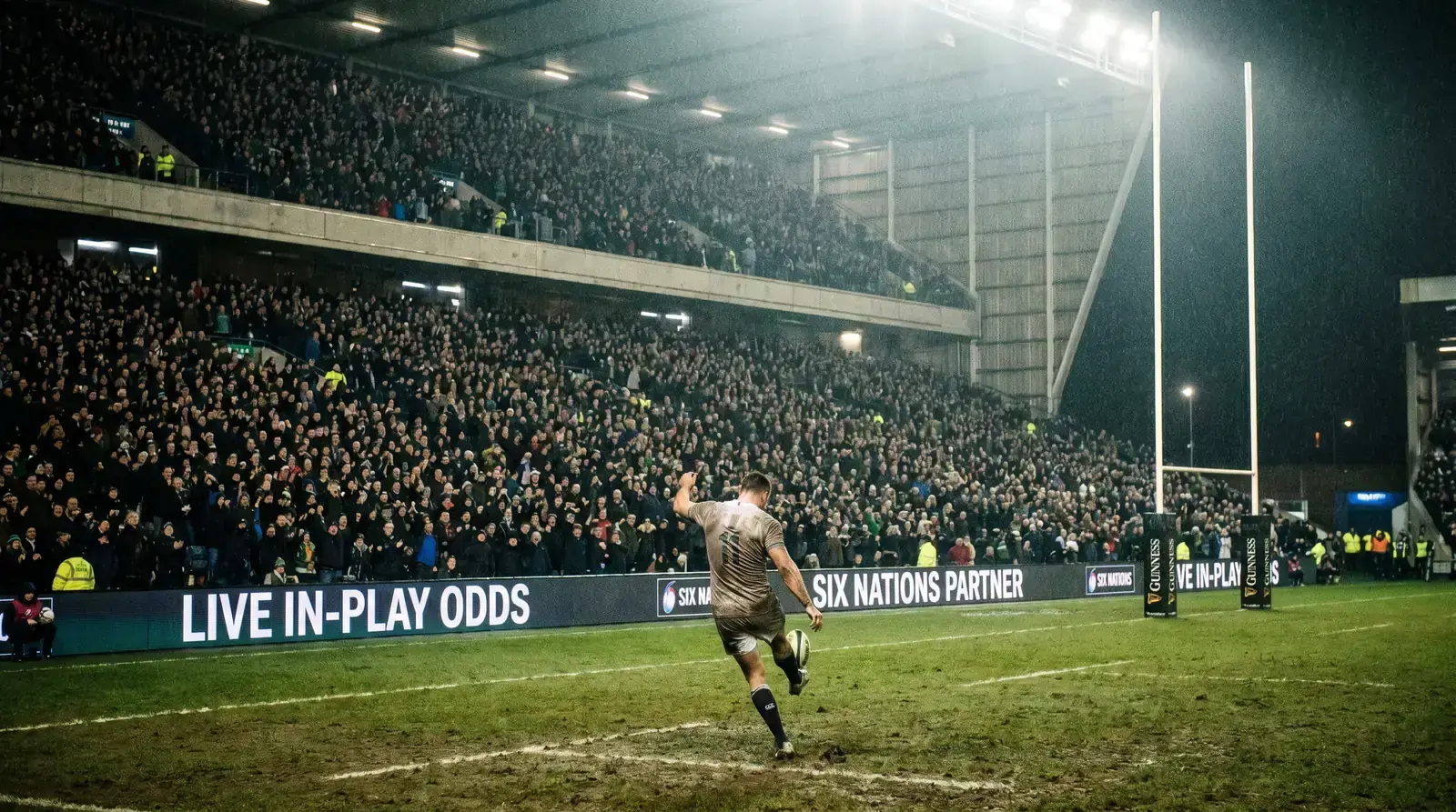 Six Nations rugby union international under floodlights with packed grandstands behind the posts